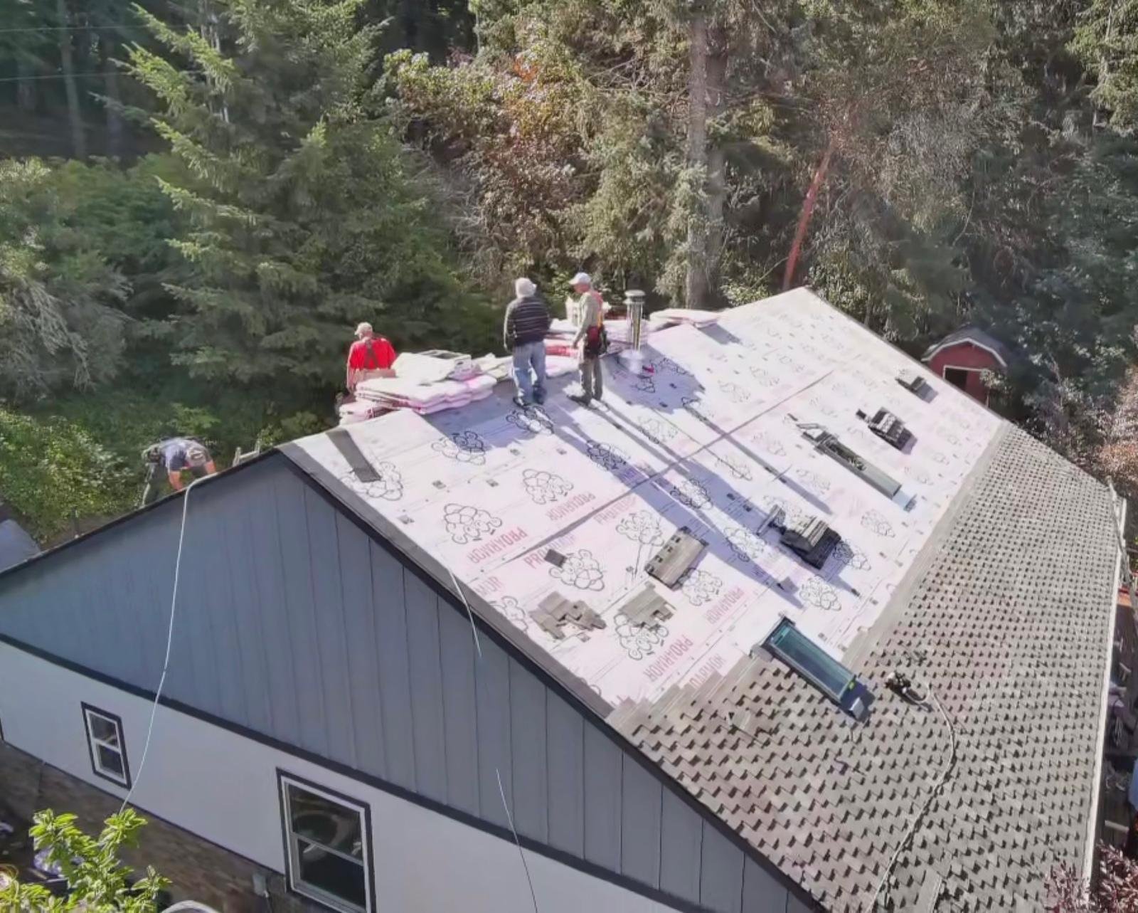 Our crew on a roof mid install, underlayment down and shingles going on